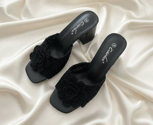 Mules nere con fascia intrecciata e fiore – vista frontale