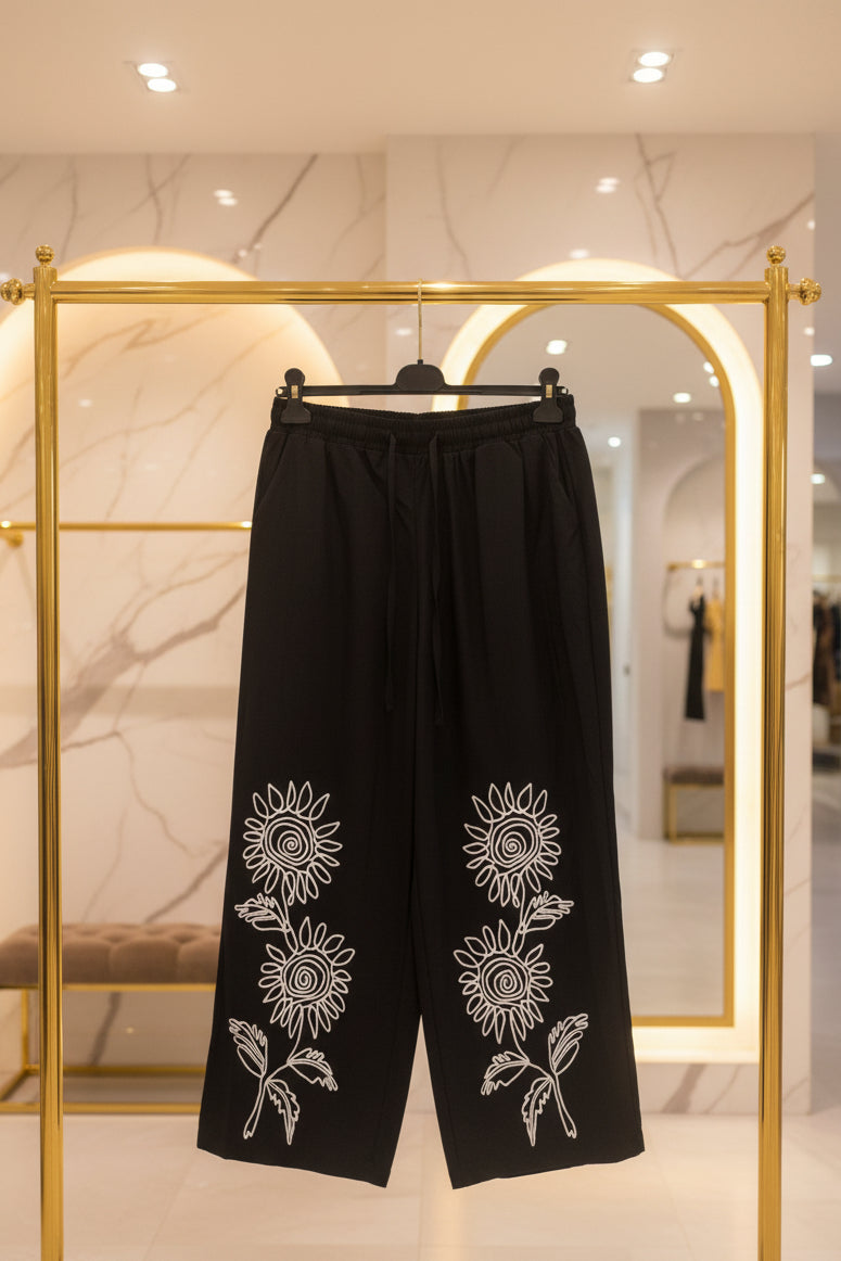 Pantaloni neri con ricami bianchi a girasoli