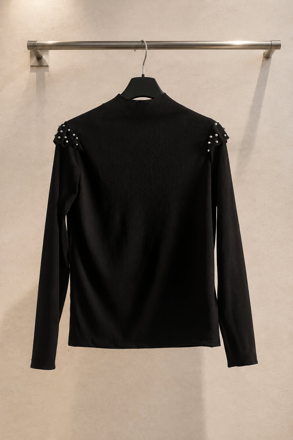 Vista posteriore di maglia nera a maniche lunghe con dettagli applicati sulle spalle