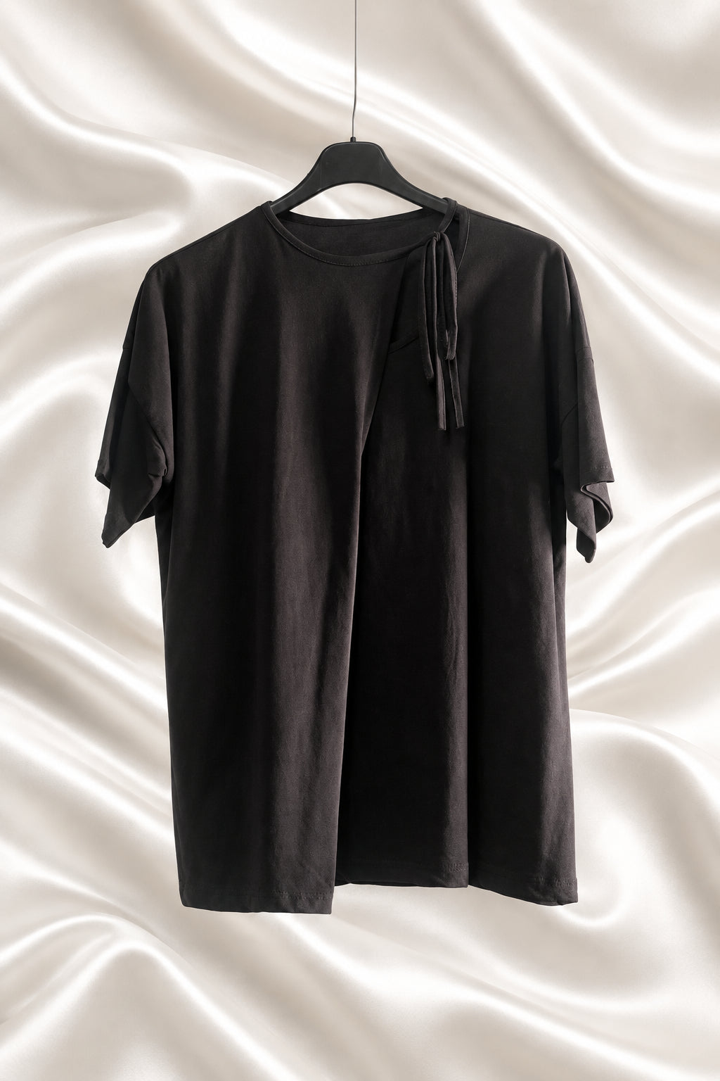 Maglia nera a maniche corte con drappeggio asimmetrico e laccetto sulla spalla