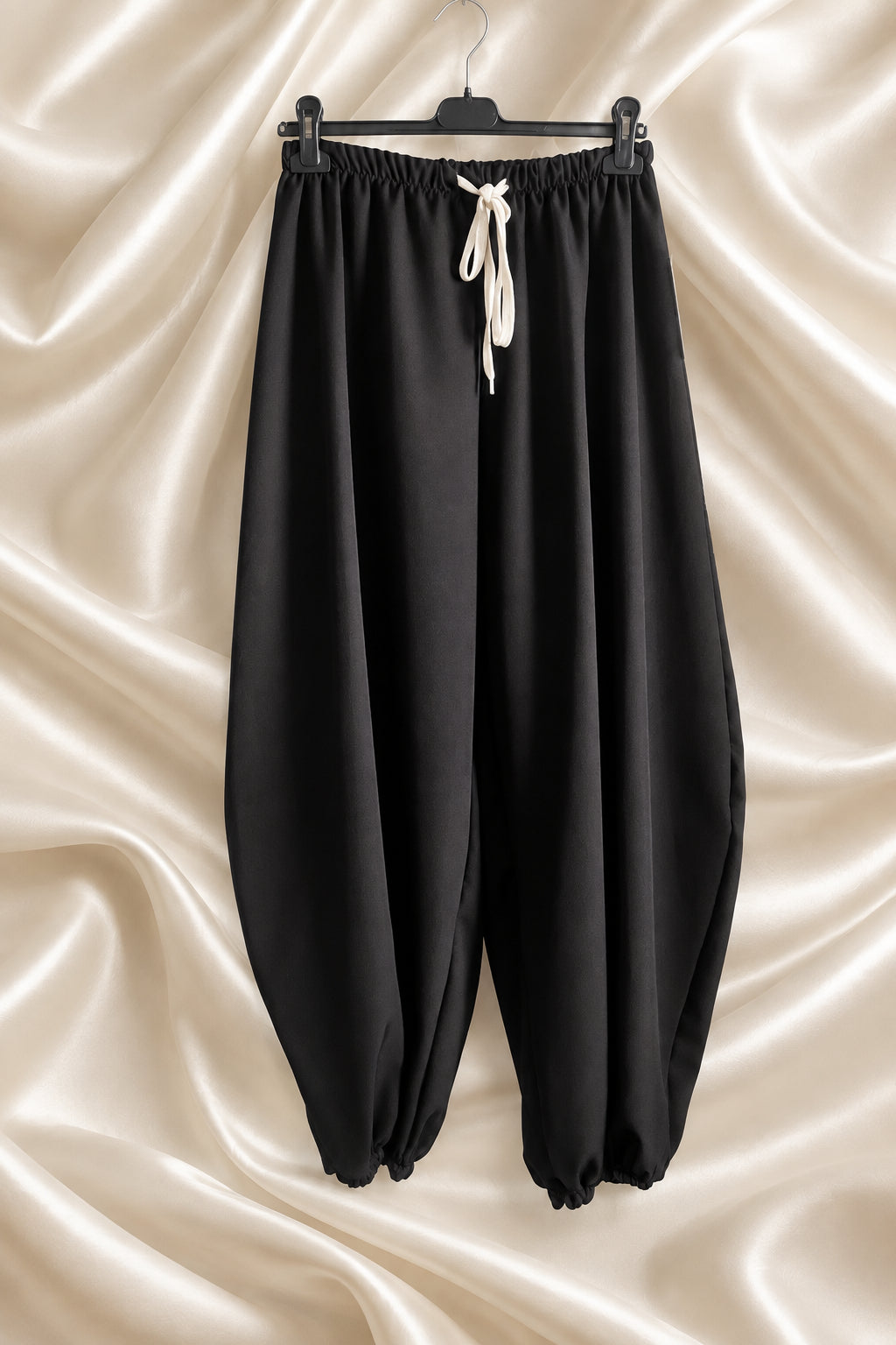 Pantaloni neri con vita elasticizzata, laccio chiaro e fondo arricciato